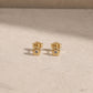 Pair of 14ct gold vermeil flower stud earrings with rainbow moonstone centre stones, displayed on a light beige stone surface with 925 butterfly backs visible.