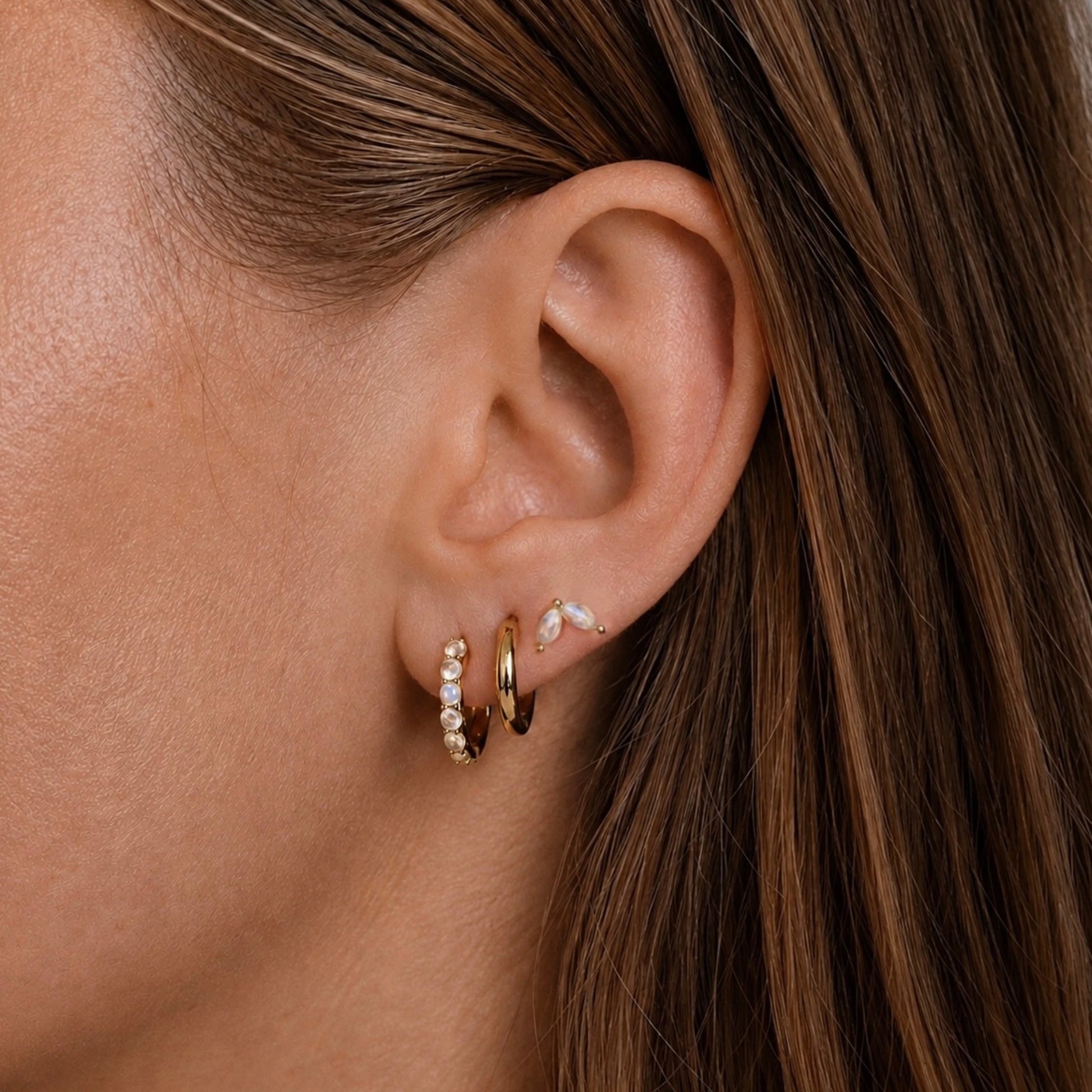 Model wearing 14ct gold vermeil rainbow moonstone hoop earrings and marquise stud earrings.
