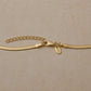 Close-up of a 14ct gold vermeil snake chain necklace featuring a lobster clasp, extender chain and Rose & Wolf branded tag on a neutral stone background.