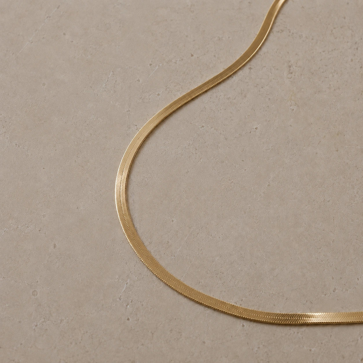 14ct gold vermeil snake chain necklace displayed on a neutral stone background.