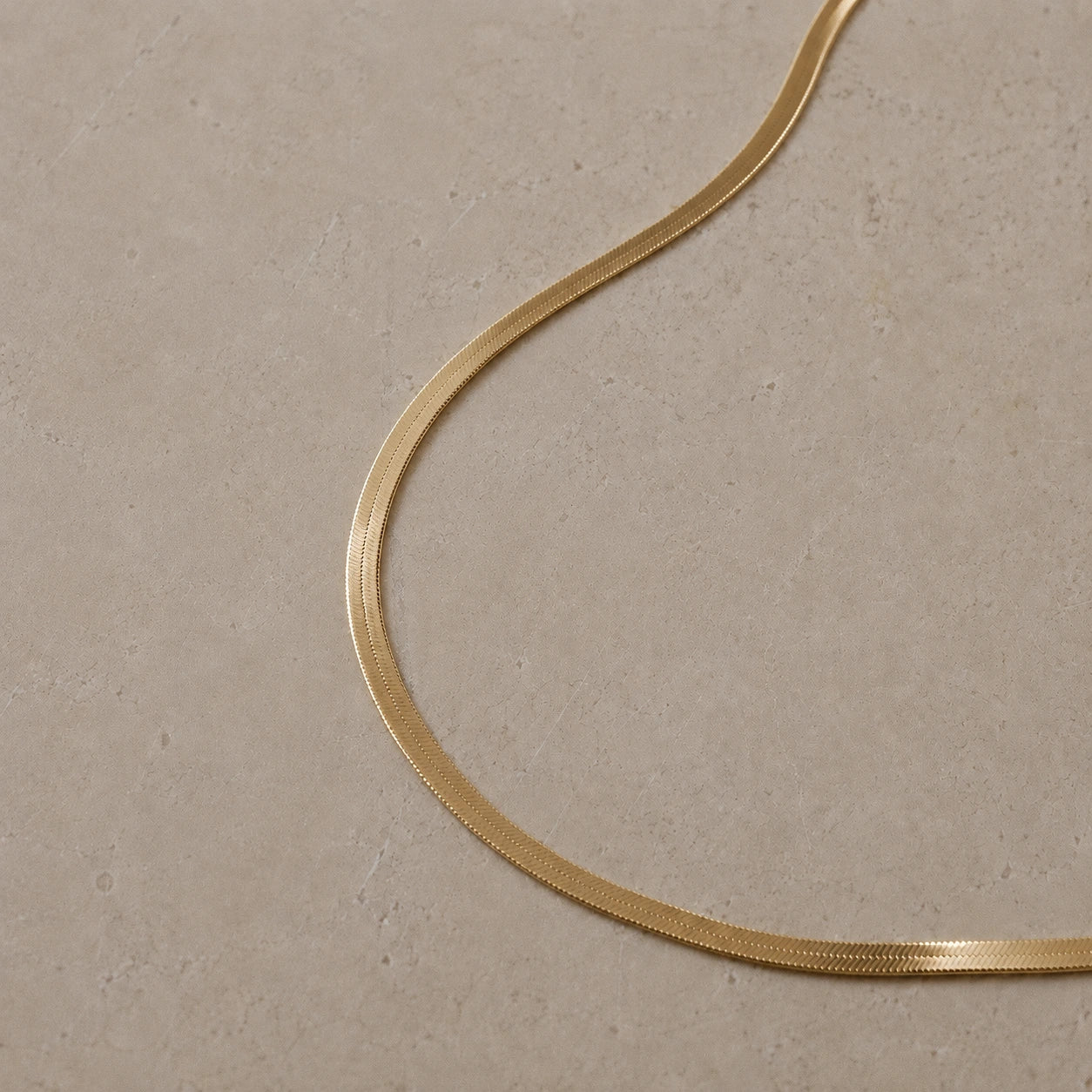 14ct gold vermeil snake chain necklace displayed on a neutral stone background.