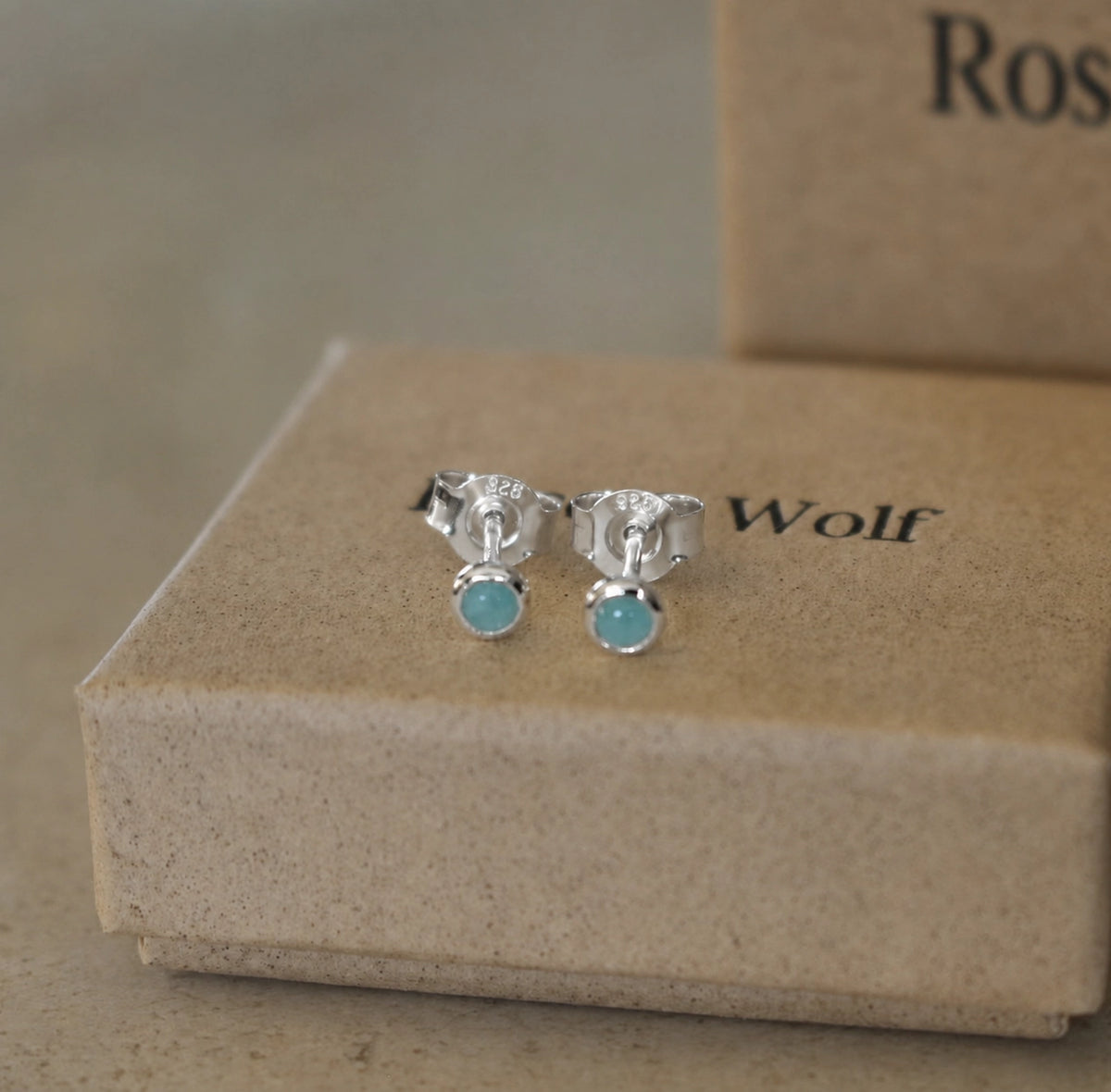 Front view of sterling silver round amazonite stud earrings with 925 butterfly backs displayed on a beige jewellery box.