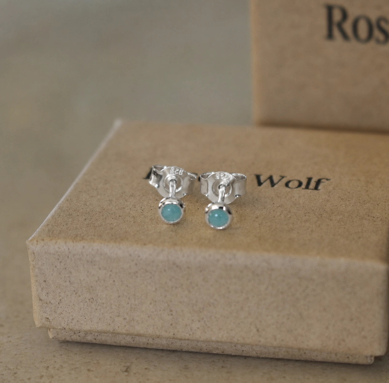 Front view of sterling silver round amazonite stud earrings with 925 butterfly backs displayed on a beige jewellery box.