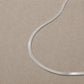 Sterling silver snake chain necklace displayed on a neutral stone background.