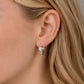 Woman wearing sterling silver starburst huggie earrings with cubic zirconia star details.
